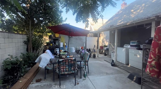 view of patio / terrace with a fenced backyard, outdoor dining area, and washing machine and dryer