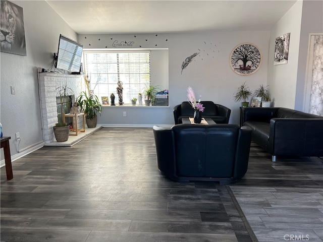 living room featuring a brick fireplace and dark hardwood / wood-style floors