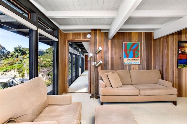 living room featuring beamed ceiling and wood walls