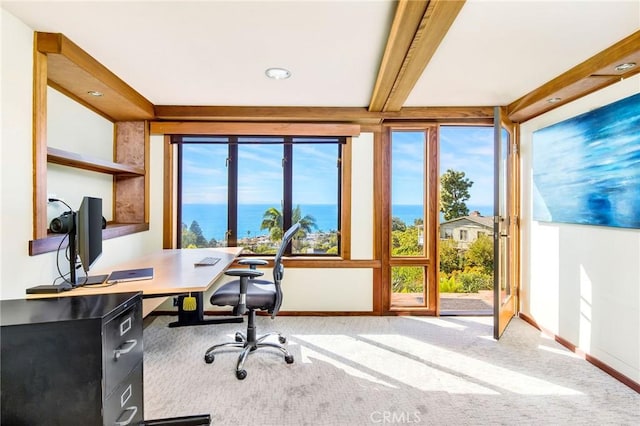 carpeted home office featuring beam ceiling