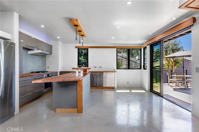 kitchen with a kitchen bar, butcher block counters, and appliances with stainless steel finishes