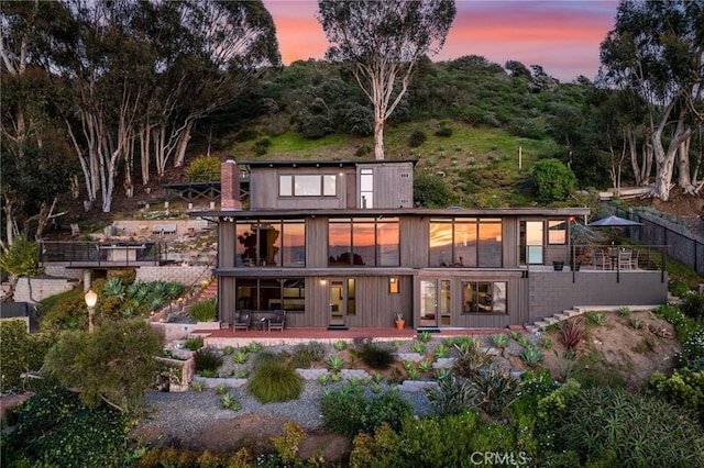 back house at dusk featuring a patio