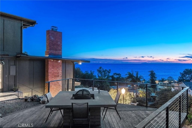 deck at dusk featuring a water view