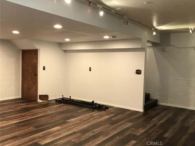 basement with dark hardwood / wood-style flooring and track lighting