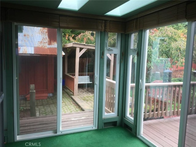 doorway to outside with carpet flooring and a skylight