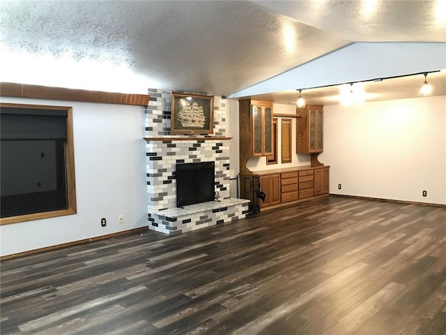 unfurnished living room featuring a fireplace, dark hardwood / wood-style flooring, a textured ceiling, and lofted ceiling