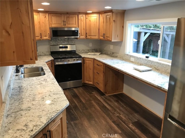 kitchen with light stone counters, sink, dark wood-type flooring, and appliances with stainless steel finishes