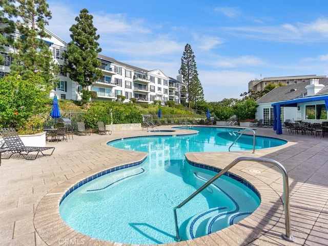 view of swimming pool featuring a community hot tub and a patio