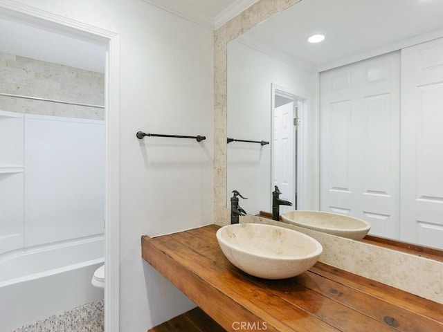 bathroom featuring washtub / shower combination, ornamental molding, and sink