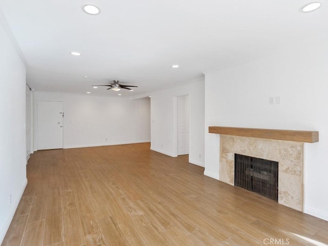 unfurnished living room with ceiling fan, light wood-type flooring, crown molding, and a fireplace