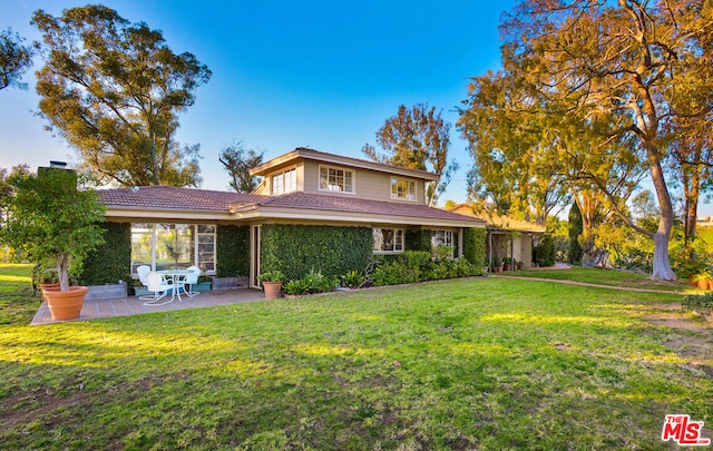 rear view of property featuring a yard and a patio area