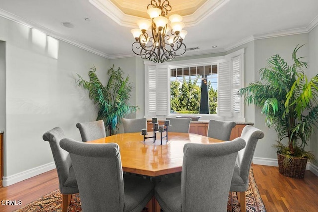 dining space with a chandelier, ornamental molding, and hardwood / wood-style flooring