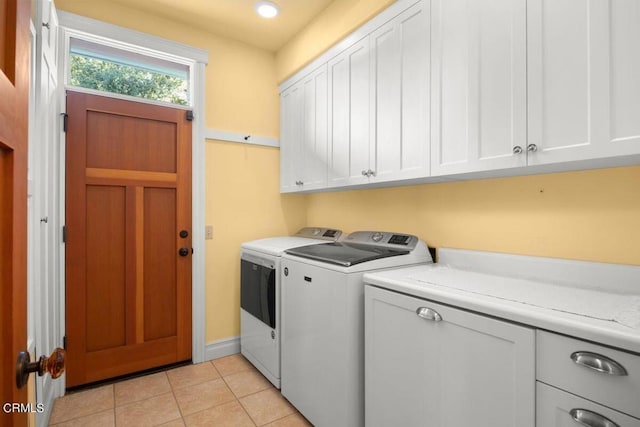 laundry room with light tile patterned flooring, washer and dryer, and cabinets