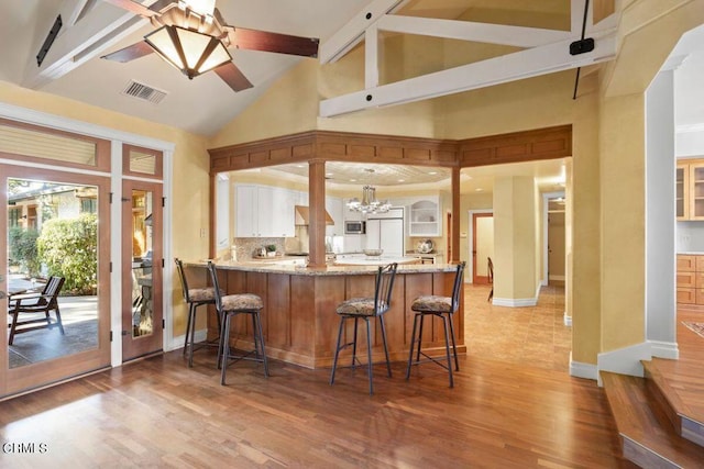 bar with high vaulted ceiling, backsplash, light wood-type flooring, and beamed ceiling