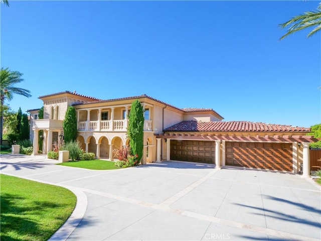 mediterranean / spanish house with an attached garage, a balcony, driveway, a tiled roof, and stucco siding