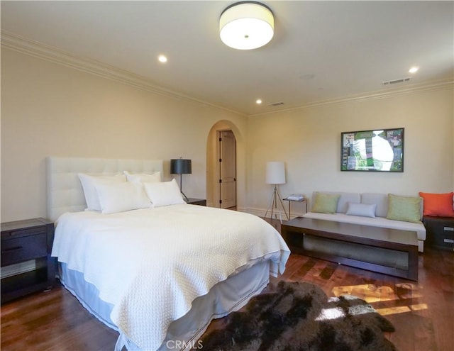 bedroom featuring ornamental molding, arched walkways, visible vents, and wood finished floors