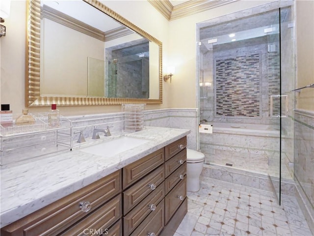 bathroom with toilet, vanity, ornamental molding, tiled shower, and wainscoting