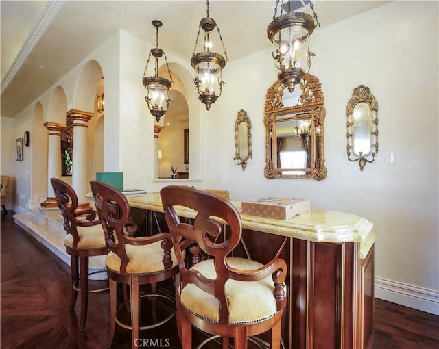 bar with baseboards, arched walkways, dark wood finished floors, and bar