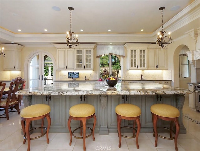 kitchen featuring tasteful backsplash, arched walkways, and cream cabinetry