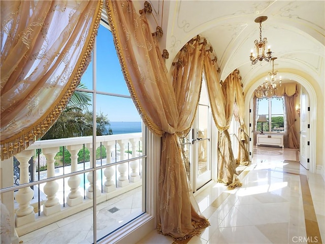 interior space with a water view, an inviting chandelier, arched walkways, and french doors