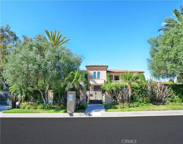 mediterranean / spanish house featuring a fenced front yard, a gate, and a tiled roof