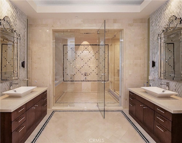 full bathroom with a stall shower, tile walls, two vanities, and a sink