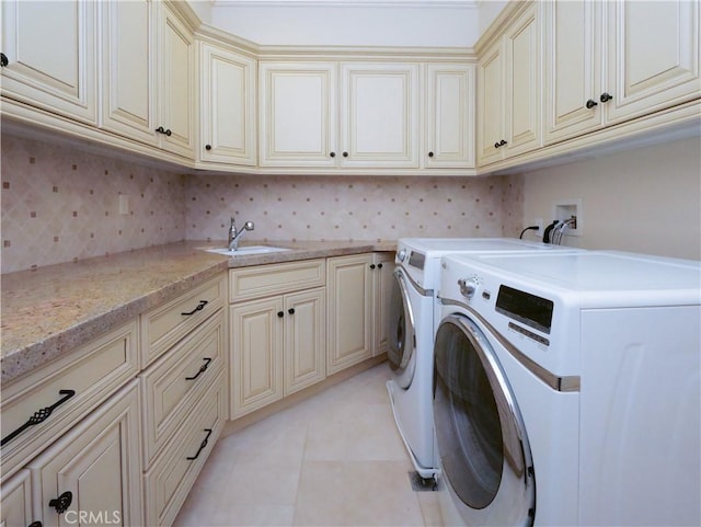 laundry area with cabinet space, light tile patterned floors, washer and clothes dryer, and a sink