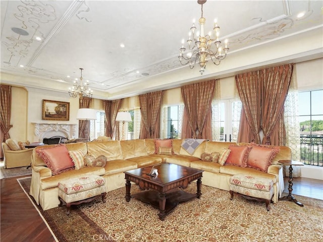 living area featuring a chandelier, a tray ceiling, plenty of natural light, and ornamental molding