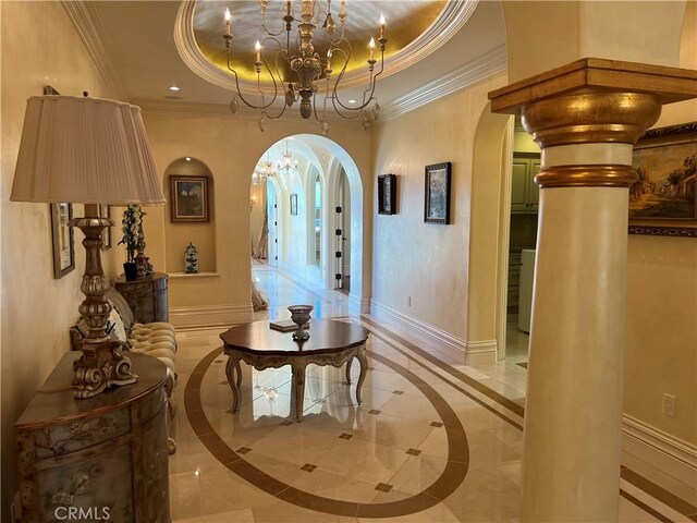 interior space with arched walkways, a raised ceiling, and baseboards