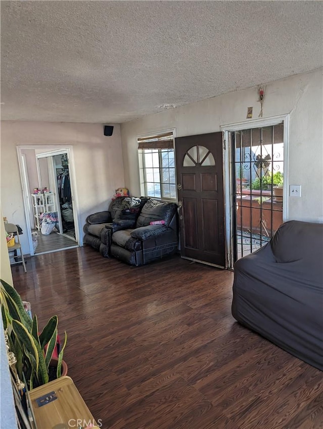 living room featuring a wealth of natural light, dark wood-type flooring, and a textured ceiling