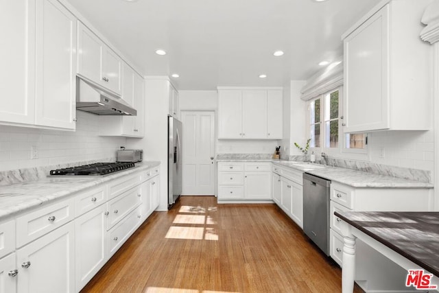 kitchen featuring white cabinetry, backsplash, light wood-type flooring, and stainless steel appliances