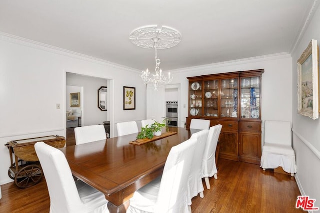 dining room with an inviting chandelier, dark hardwood / wood-style flooring, and ornamental molding