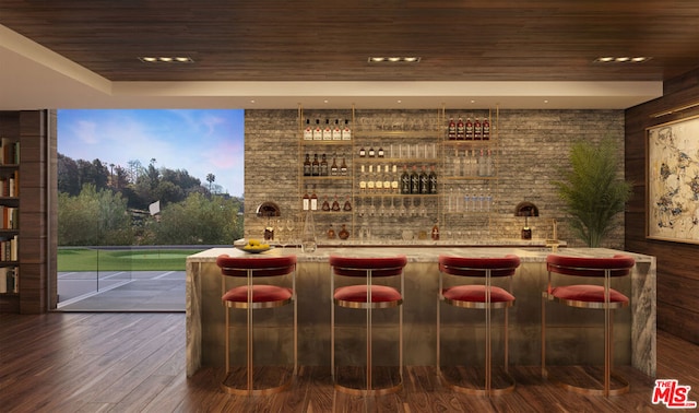 bar with tasteful backsplash, light stone counters, dark wood-type flooring, and wooden ceiling