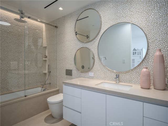 full bathroom featuring toilet, shower / bath combination with glass door, and vanity