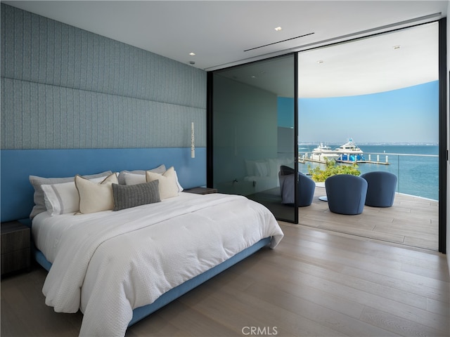 bedroom featuring a water view and hardwood / wood-style floors