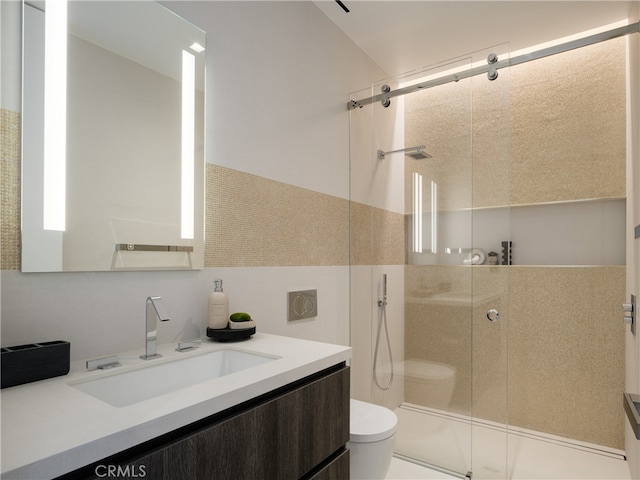 bathroom with toilet, a shower with shower door, and vanity