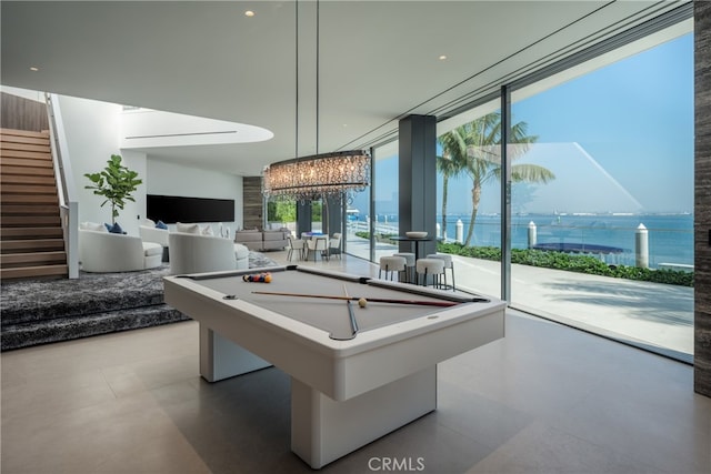 game room featuring a chandelier, light tile floors, billiards, floor to ceiling windows, and a water view