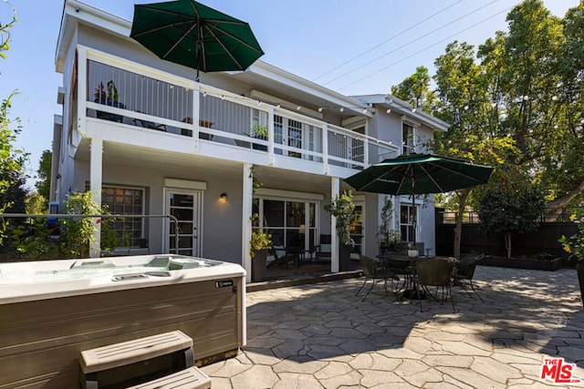 rear view of house featuring a balcony, a hot tub, and a patio area