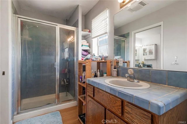 bathroom with hardwood / wood-style floors, vanity, and walk in shower