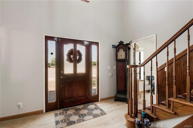 foyer entrance with light wood-type flooring and a towering ceiling