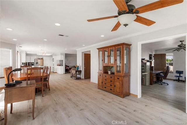 dining area with crown molding, ceiling fan, and light wood-type flooring