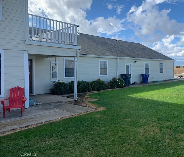 rear view of property featuring a lawn, a patio area, and a balcony