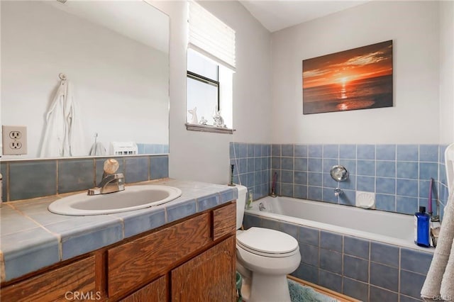 bathroom featuring tiled bath, vanity, and toilet