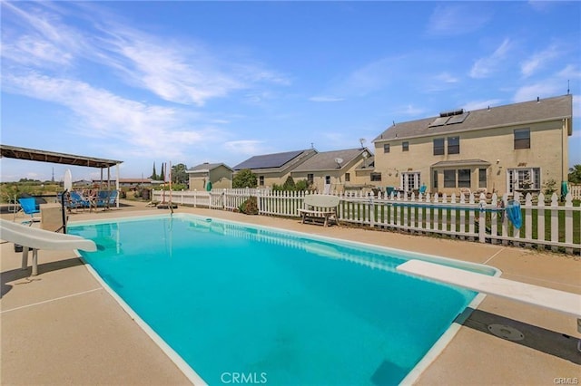 view of swimming pool featuring a patio area, a diving board, and a water slide