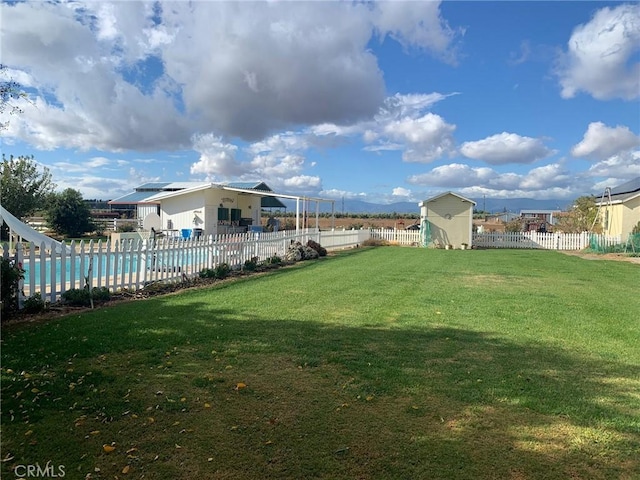 view of yard featuring a fenced in pool and a shed