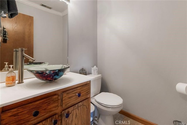 bathroom with toilet, vanity, and ornamental molding