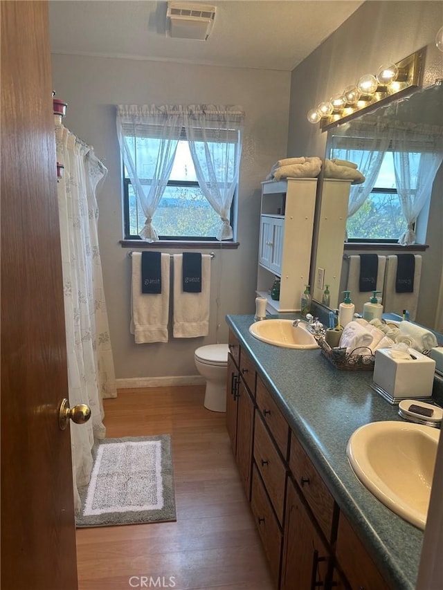 bathroom featuring toilet, plenty of natural light, vanity, and hardwood / wood-style flooring