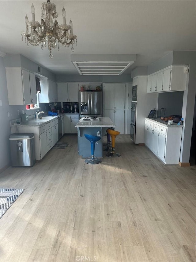 kitchen with appliances with stainless steel finishes, light wood-type flooring, sink, a kitchen island, and a breakfast bar area