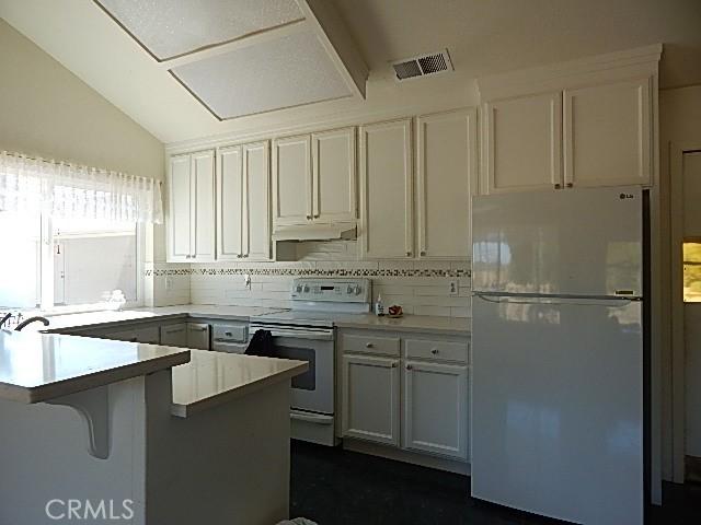 kitchen with lofted ceiling, white cabinetry, white electric range oven, and fridge