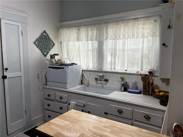 kitchen with gray cabinetry, tasteful backsplash, and sink